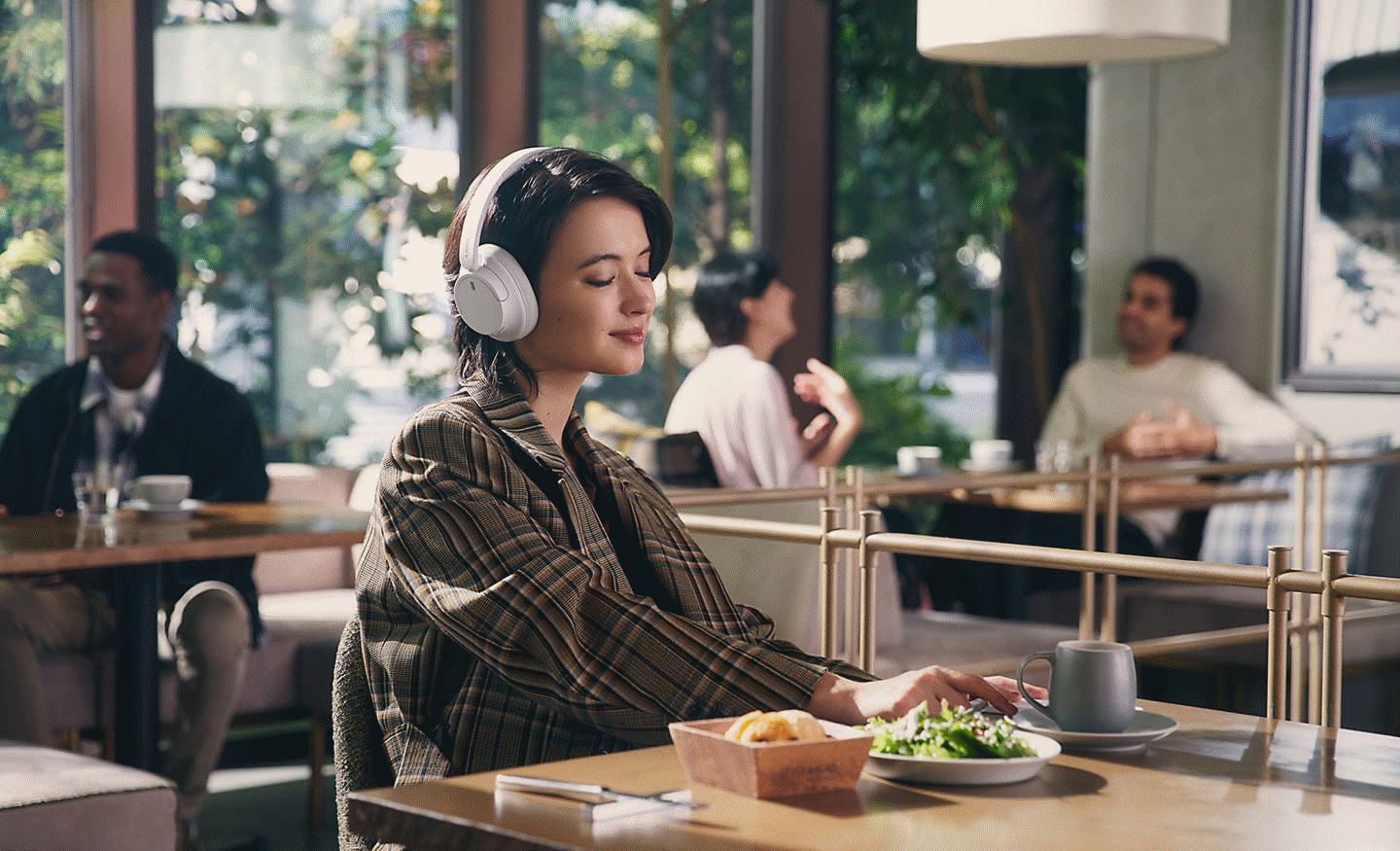 음식점에서 화이트 색상의 소니 WH-CH720 헤드폰으로 음악을 감상하고 있는 여성의 이미지