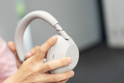 플래티넘 실버로 마감한 WH-1000XM6 헤드폰을 들고 있는 손의 클로즈업 이미지