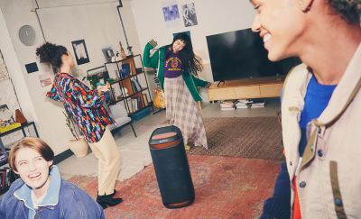 Image of four people in a living room dancing around the SRS-XV800 speaker with red ambient lighting