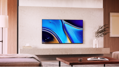 Настінний телевізор над мармуровим постаментом із зображенням жовтих, синіх і чорних крапель води та столом із книгою на передньому плані