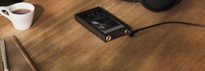 Sony NW‑ZX900 audio player paired with headphones on a wooden café table