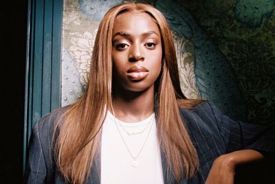 An image of Cat Burns standing in front of a textured background.