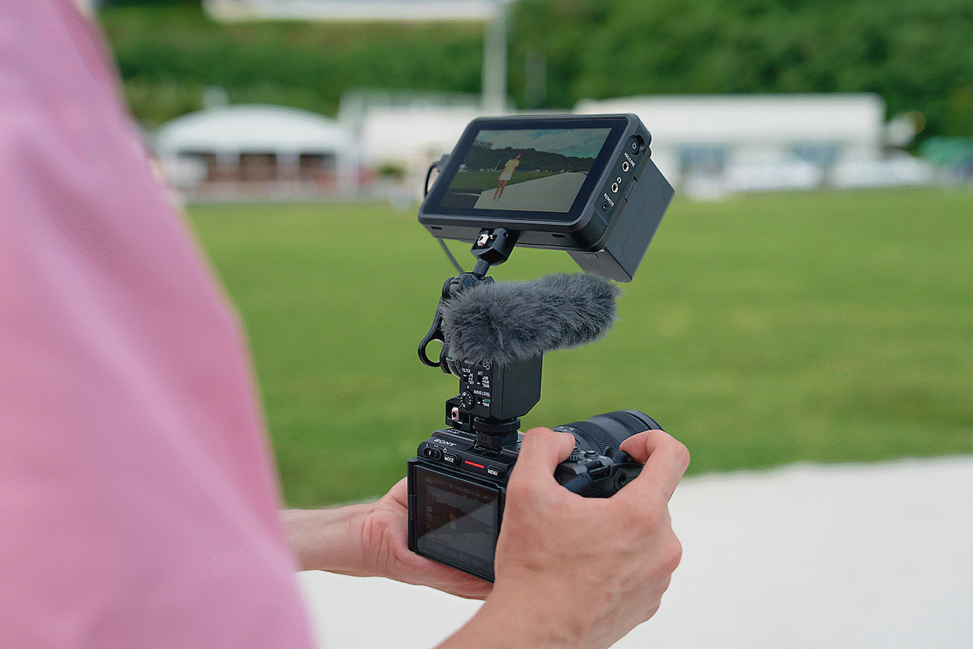 Egy mikrofonnal és monitorral felszerelt kamerát tartó fotós