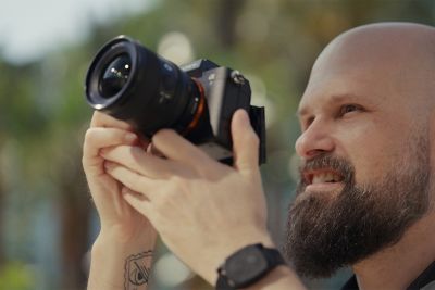 A close-up of a man holding a camera and trying to shoot a video.