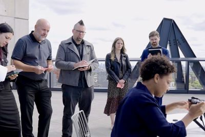 Un grupo de personas observando una demostración de una cámara en un taller de diseño inclusivo.