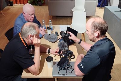 Tres hombres revisan y prueban una cámara y un micrófono.