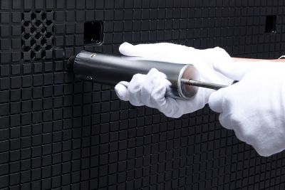 Close-up image of plastic panel, with a person wearing gloves holding a tool.