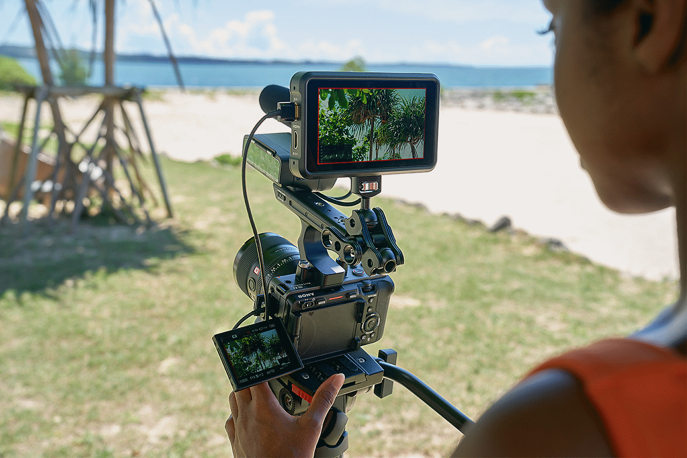 Fotograf som filmar på en gräsbevuxen plats med handtag och skärm