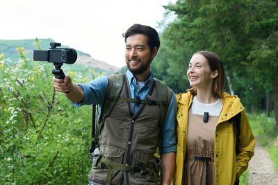 Fotografía en la que se muestra a un hombre y una mujer con micrófonos puestos sonriendo a la cámara que tiene un receptor acoplado