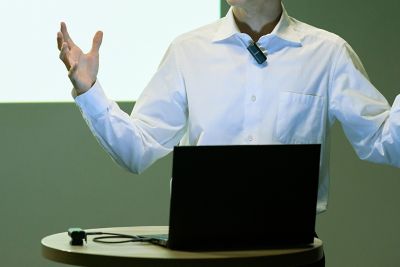 Foto de un hombre que realiza una presentación con un micrófono en la ropa