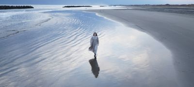 Issız bir kumsalda yürüyen kadın