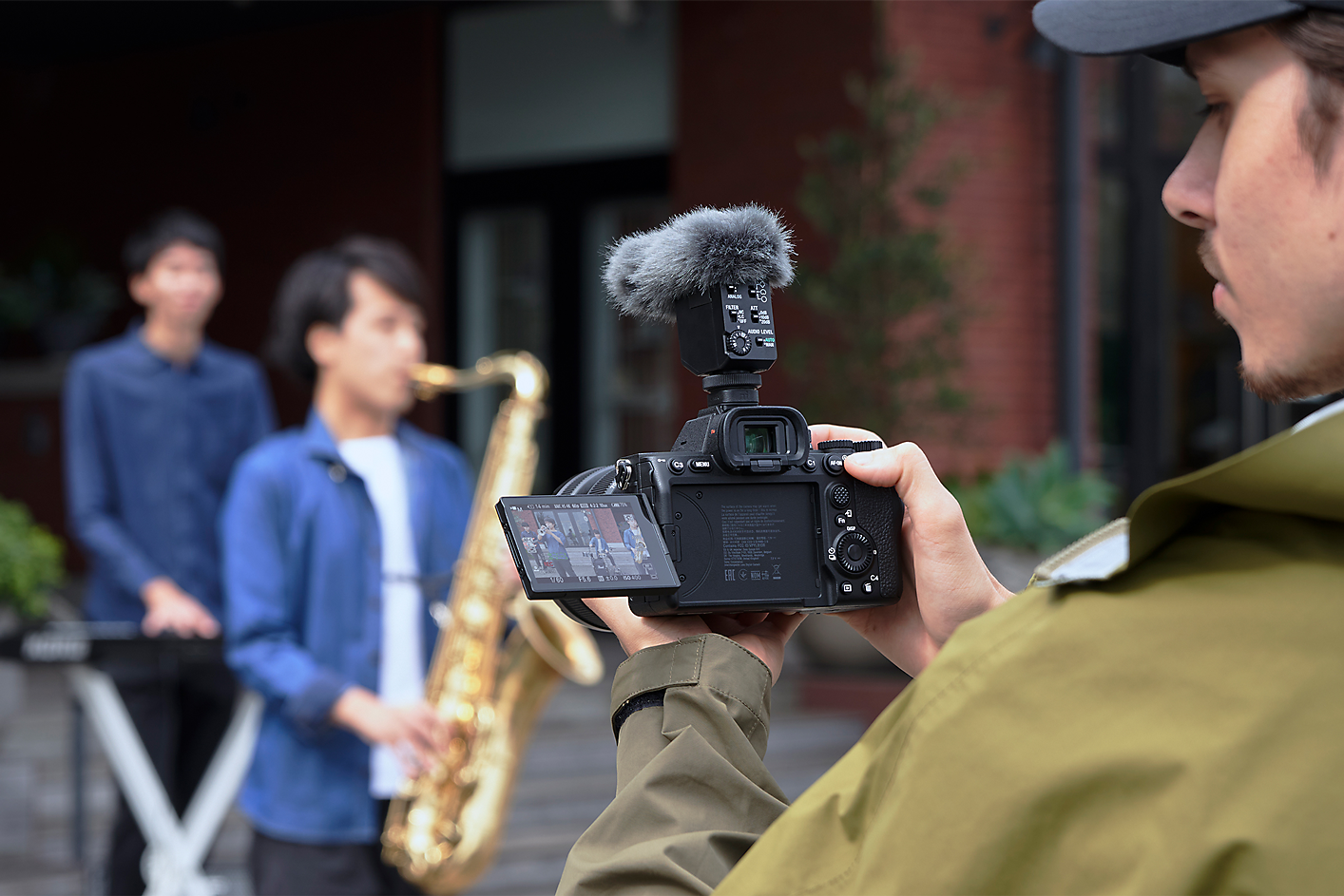 Obrázok kameramana, ktorý natáča hudobníkov v jednosmernom režime s mikrofónom ECM-B10 pripevneným ku kamere.