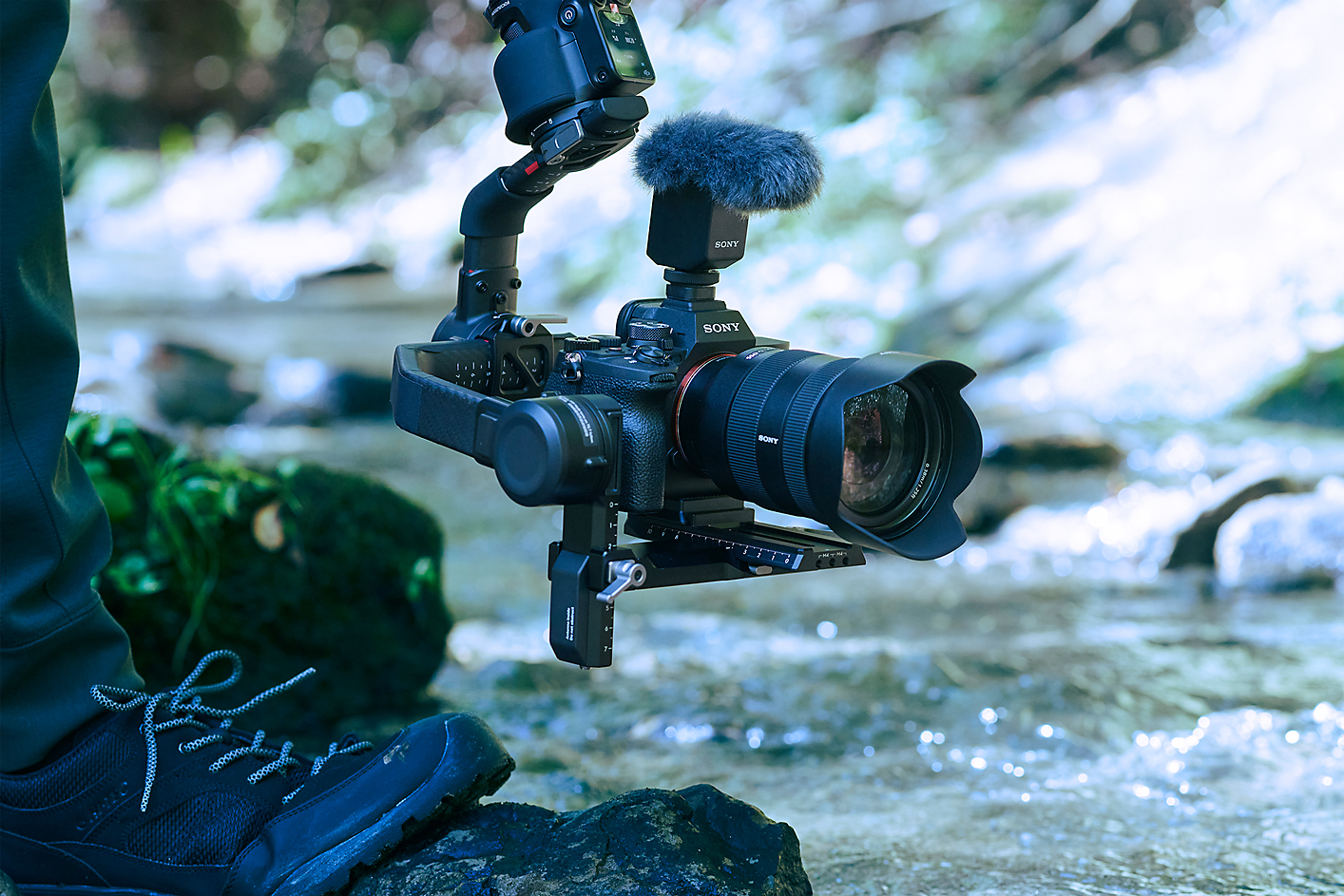 Imagem de uma pessoa a utilizar uma câmara montada num gimbal para captar som próximo de um riacho.