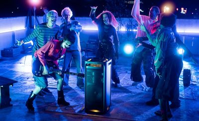 Una persona tocando una guitarra eléctrica enchufada a un ULT TOWER 9 mientras las personas alrededor bailan