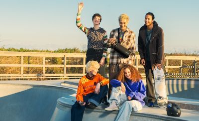 Cinco personas en una pista de patineta reunidas en torno a una persona que lleva un parlante ULT FIELD 5 en el hombro