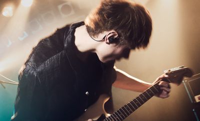 Guitarrista tocando en el escenario con unos audífonos Sony negros