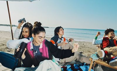 A group of young people dancing at the beach while listening to the ULT FIELD 1 portable speaker.