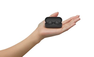 A hand is holding a pair of the WF-C510 in its respective earbuds case