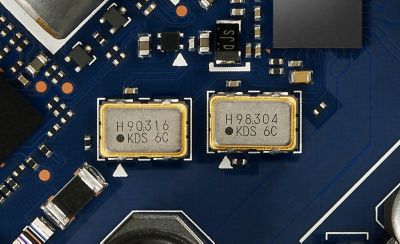 Close‑up of two compact low-phase-noise crystal oscillators on audio PCB