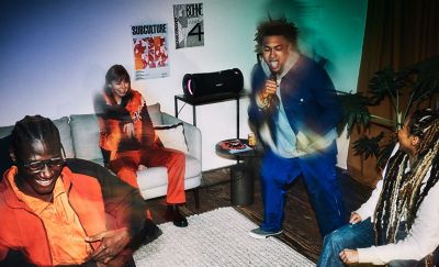 Young people at a house party using the ULT FIELD 7 portable speaker as a karaoke machine.