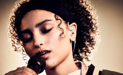Persona que canta al micrófono con unos audífonos Sony transparentes