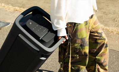 A person using the integrated top handle on the TOWER 9 speaker to pull it behind them