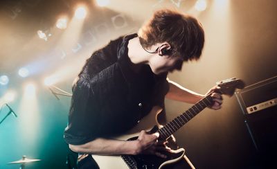 Guitarrista tocando en el escenario con unos audífonos Sony negros