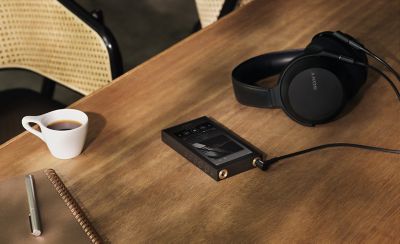 Sony NW‑ZX900 audio player paired with headphones on a wooden café table