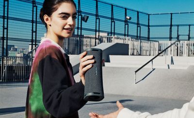 Young person handing the ULT FIELD 1  portable speaker to a friend at a skate park.