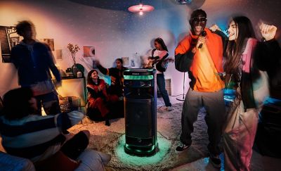 Young people at a party singing karaoke with the microphone plugged into the ULT TOWER 10 speaker.