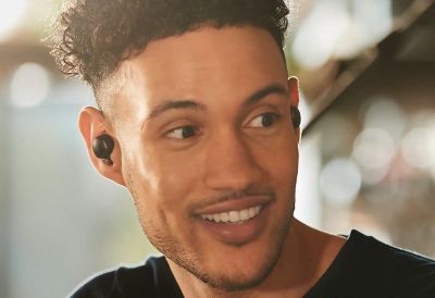 Мужчина и женщина разговаривают. Мужчина в наушниках WF-1000XM4.