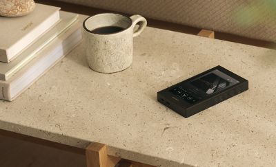 Sony NW‑ZX900 resting on a living‑room coffee table beside a mug and stacked books