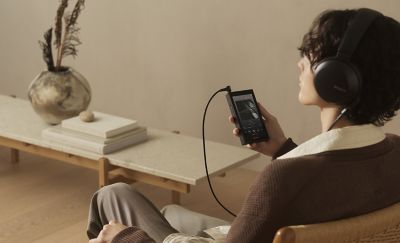 Man relaxing at home, listening to audio via Sony NW‑ZX900 and wired headphones