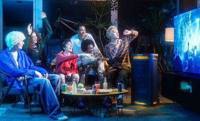 Một nhóm người đang xem và thưởng thức buổi biểu diễn trên TV, với nhạc được phát ra từ loa TOWER 9AC