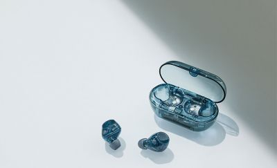 El estuche de carga azul transparente se muestra junto al par de audífonos azules transparentes