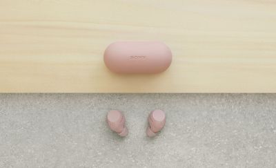 Se muestra el estuche de carga rosa cerrado al lado del par de audífonos rosa