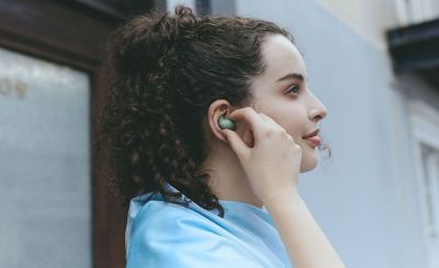 A young woman adjusting her LinkBuds Fit earbud.