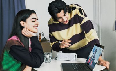 Two people making a video call on a laptop with the ULT FIELD 1  portable speaker providing the audio.