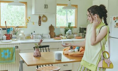 A young woman standing in her kitchen while wearing her LinkBuds Fit earbuds.