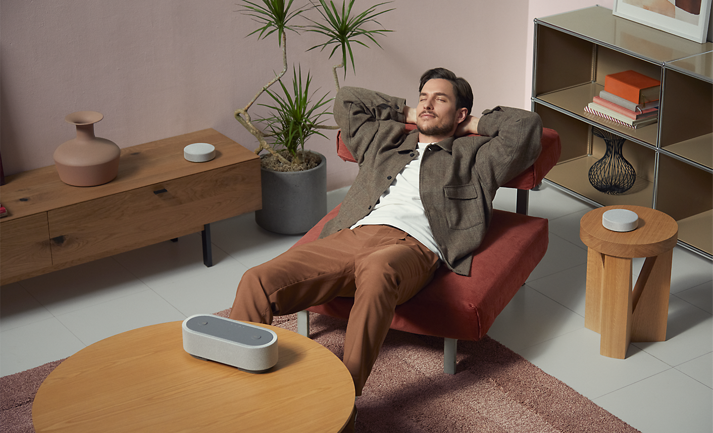 Image of a person laying on an accent chair, surrounded by the three HT-AX7 speakers