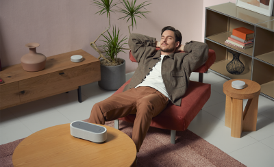 Image d'une personne assise dans un fauteuil, entourée des trois enceintes HT-AX7