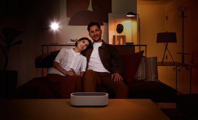 Image d'un couple assis sur un canapé, entouré des trois enceintes HT-AX7