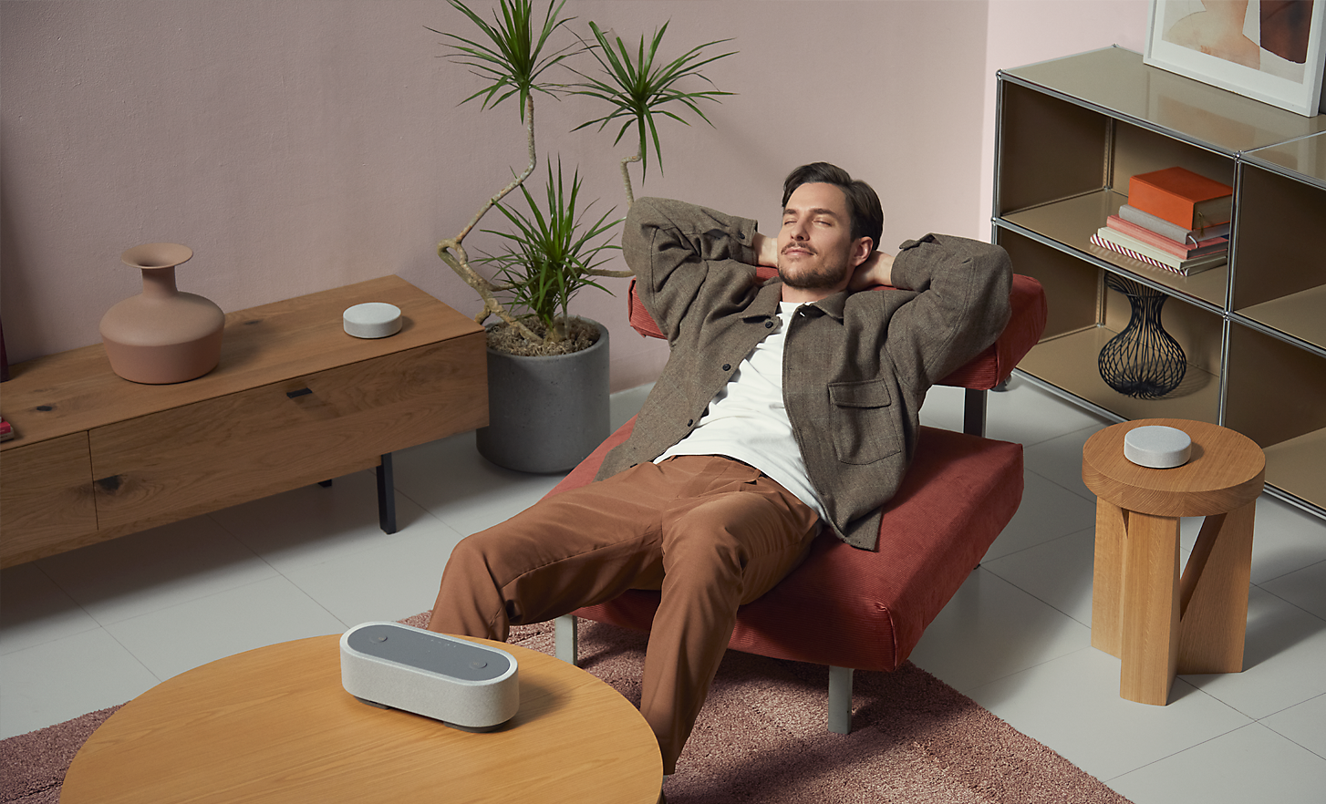 Image of a person laying on an accent  chair, surrounded by the three HT-AX7 speakers