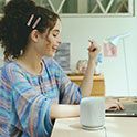 Una mujer joven trabajando con una laptop en un escritorio con el parlante LinkBuds en primer plano.