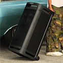 A person pulling the TOWER 9 speaker behind them using the 2 castors on the base of the speaker