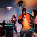 Young people at home watching a concert on television and using the ULT TOWER 10 speaker to provide the sound.