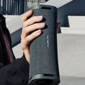 Young person handing the ULT FIELD 1 portable speaker to a friend at a skate park. 