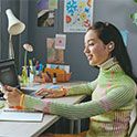 Girl sitting at desk with her laptop and phone listening with ear buds