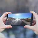 Dłonie trzymające telefon z wyświetlonym obrazem drogi