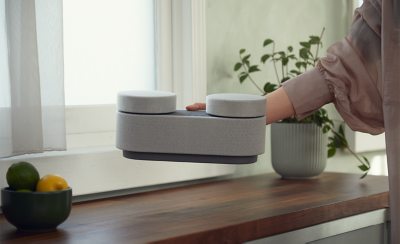 Image du système HT-AX7 placé sur une table d'appoint avec les enceintes arrière attachées